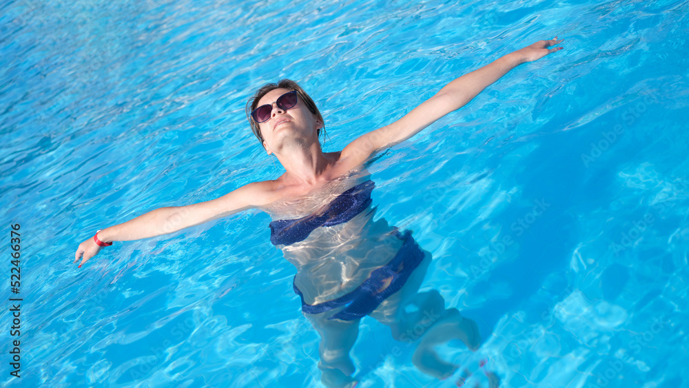 Happy beautiful woman in sunglasses relaxing in pool water