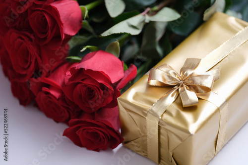 Red rose flowers and gift box on table