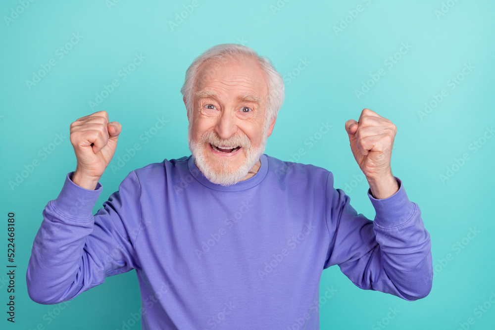Portrait of delighted astonished person raise fists shout yes success isolated on cyan color background Portrait of delighted astonished person raise fists shout yes success isolated on cyan color background