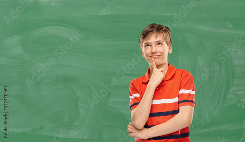 education, school and people concept - portrait of happy thinking student boy in red polo t-shirt over green chalkboard background