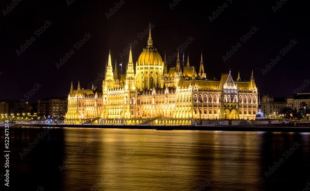 Lighted Hungarian parliament building at night and flowing river Dunube. Long exposure photo