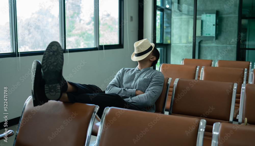 Young traveler sleeping in airport while waiting airline flight to travel at airport terminal.