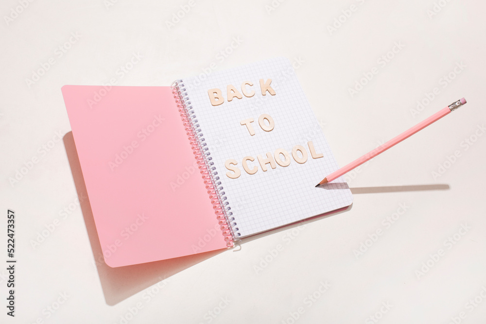 The inscription back to school on a pink notepad with a pencil The inscription back to school on a pink notepad with a pencil