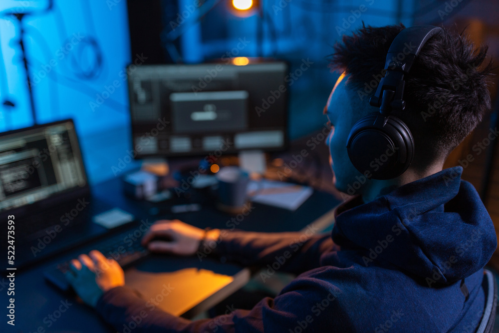 cybercrime, hacking and technology concept - close up of male hacker in dark room writing code or using computer virus program for cyber attack cybercrime, hacking and technology concept - close up of male hacker in dark room writing code or using computer virus program for cyber attack