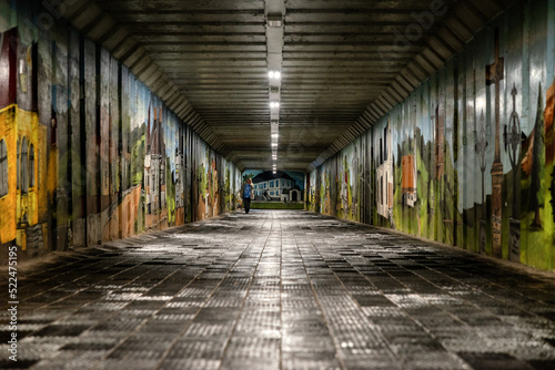 Pedestrians walking in long underpass with graffitti on walls in town Liptovsky Hradok, Slovakia