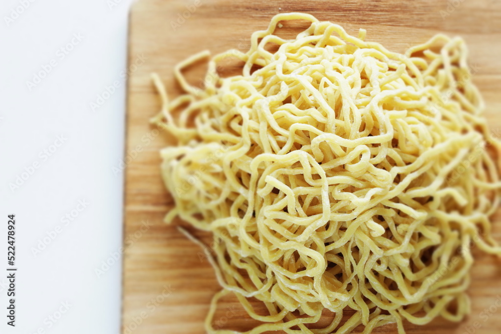 Chinese food, egg noodles on wooden chopping board Chinese food, egg noodles on wooden chopping board