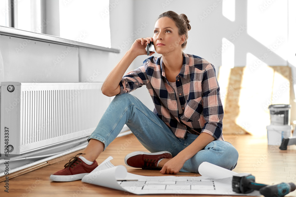repair, people and real estate concept - woman with blueprint and pencil sitting on floor at home and calling on smartphone