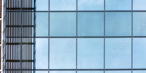 local corporate construction panoramic windows of blue colour reflect sky and summer sunlight near metal decoration