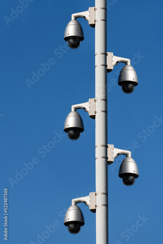 Several surveillance cameras on a metal pole against a blue sky