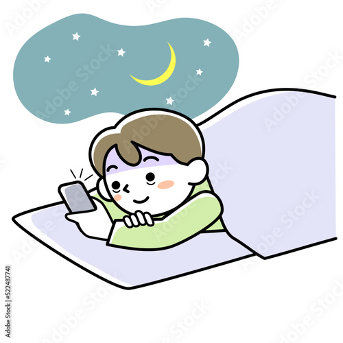 夜中に布団の中でスマホを見て夜更かしする若い男性