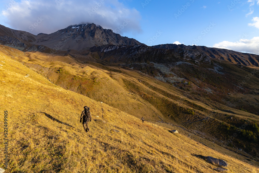 An alone hunter walking in the Alps mountains in a beautiful morning. An alone hunter walking in the Alps mountains in a beautiful morning.