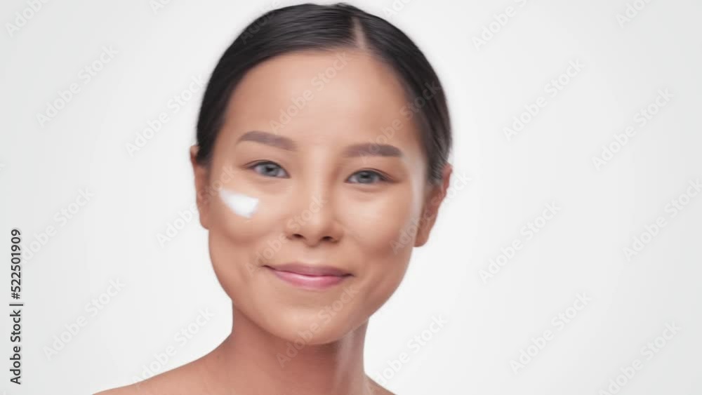 Concept for fresh moisturized skin. Beautiful close up cosmetic face happy healthy model. Young asian woman look at camera and take care of her skin. Happy healthy model on white background in studio. Concept for fresh moisturized skin. Beautiful close up cosmetic face happy healthy model. Young asian woman look at camera and take care of her skin. Happy healthy model on white background in studio.