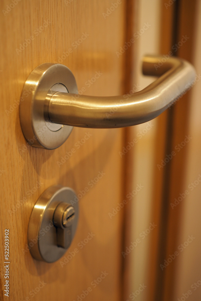 Chrome door handle with key lock on wooden door Chrome door handle with key lock on wooden door