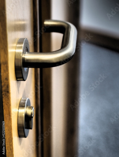 Chrome door handle with key lock on wooden door