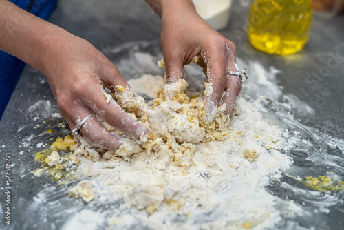 Beautiful young female hands break eggs into flour to knead a beautiful dough.