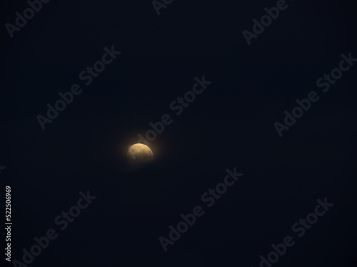 Moon, part obscured by cloud, hangs in starless night sky. Mystical in the darkness. photo
