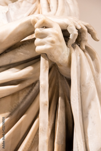 Close-up on hands of ancient roman statue holding a stick