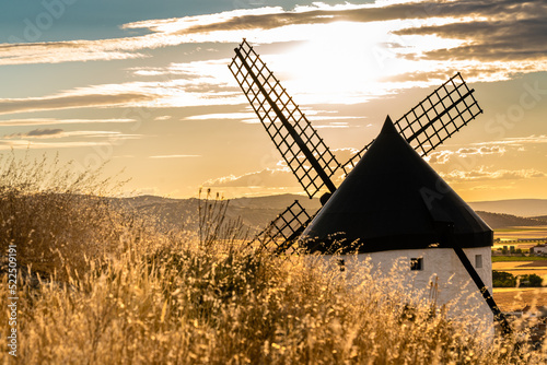 Old windmill photographed at golden hour. Beautiful warm colours on the field and the sky. Beautiful nature wallpaper.