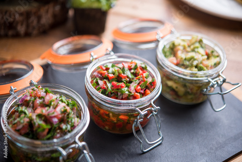 Assorted chopped vegetables served in jars on stone board