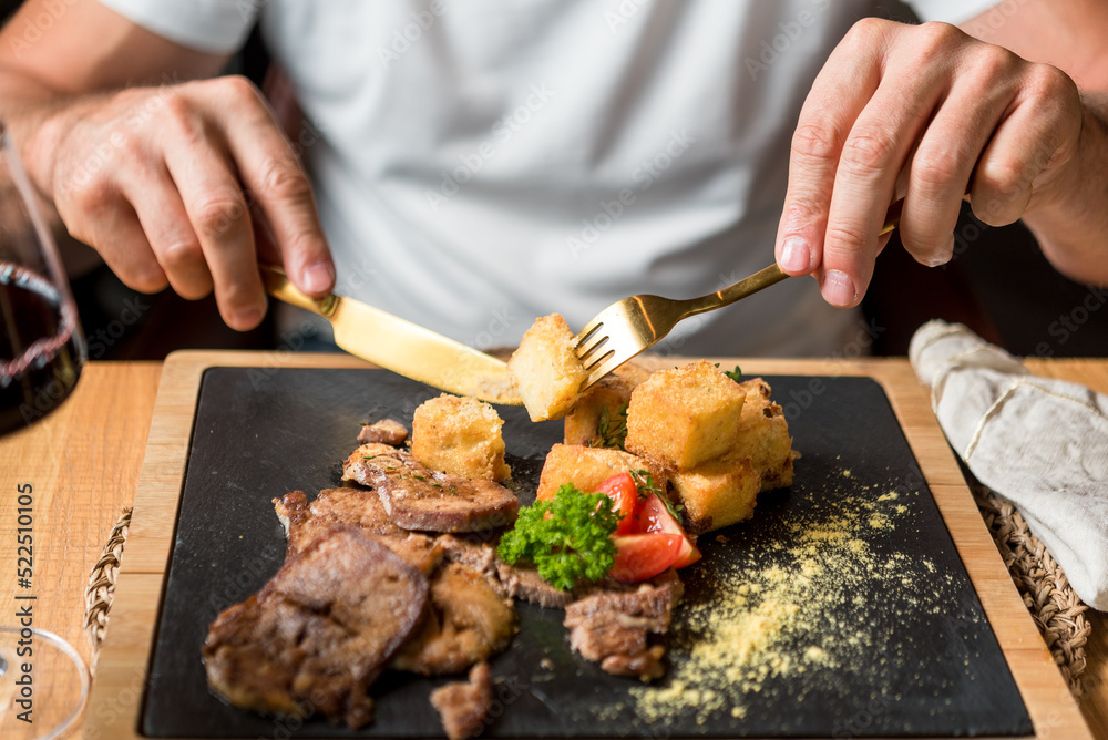 Man eating delicious beef dish complimented with red wine