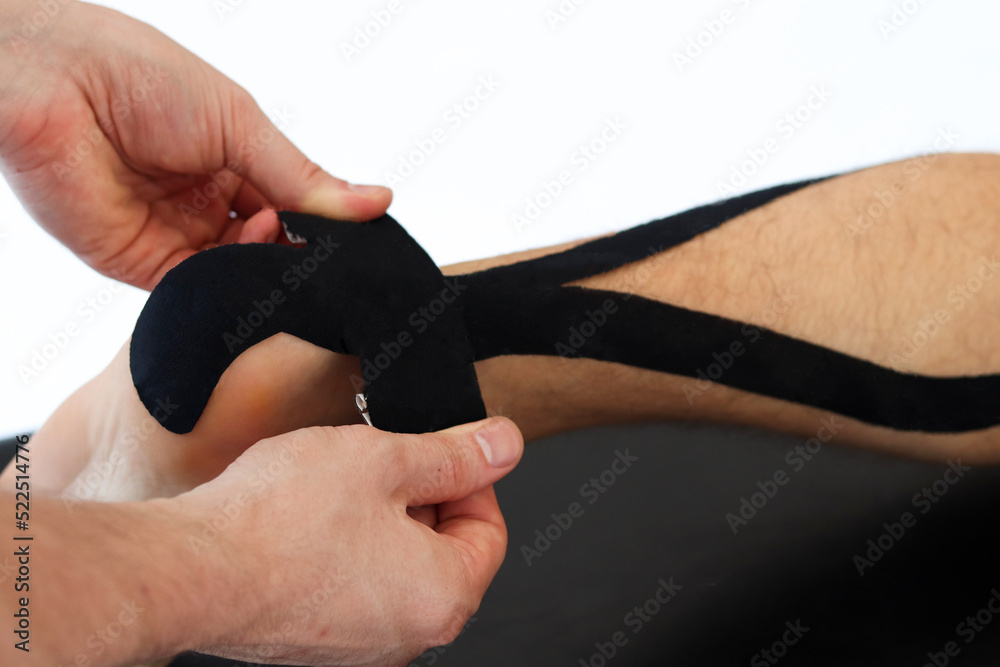 Kinesiology taping treatment with black tape on male patient injured