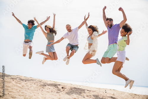 Full length photo of group excited overjoyed carefree buddies jumping enjoy sunny weather sand beach chill outside