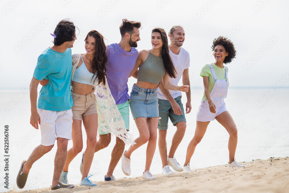 Full size portrait of group cheerful friendly buddies hug walking sand beach speak chatting enjoy free time outside Full size portrait of group cheerful friendly buddies hug walking sand beach speak chatting enjoy free time outside
