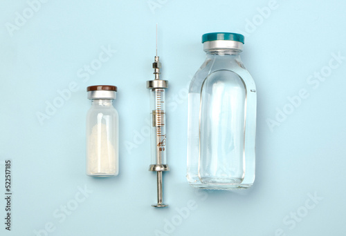 Set for injections. Flat lay on a blue background. Vintage syringe, novocaine, and an antibiotic. Medical background photo