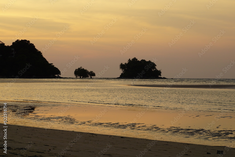 sunset on the beach with an island in the background