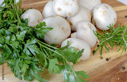 Fresh white champignons mushrooms, parsley and thyme on cutting board. Vegan concept.