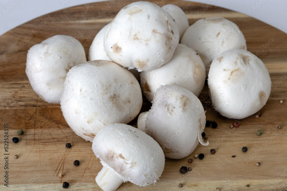 Fresh white champignons mushrooms on cutting board. Vegan concept.