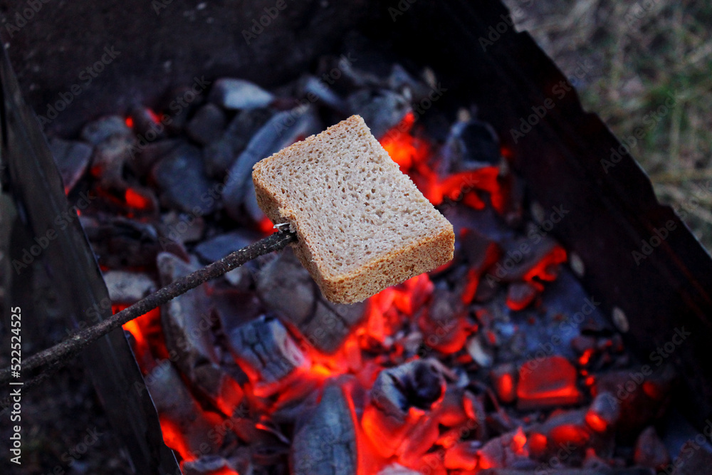 fry bread on a campfire on a camping trip, bread impaled on a stick over coals, cook brown bread on an open fire, a slice of bread fried on a fire, roast bread over hot coals fry bread on a campfire on a camping trip, bread impaled on a stick over coals, cook brown bread on an open fire, a slice of bread fried on a fire, roast bread over hot coals
