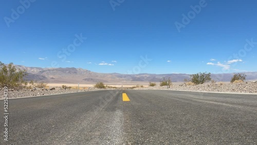 SLOW MOTION SHOT - State Route 190 crossing Panamint Valley in Death Valley National Park, California, United States. Empty desert road in Death Valley with clear blue sky.