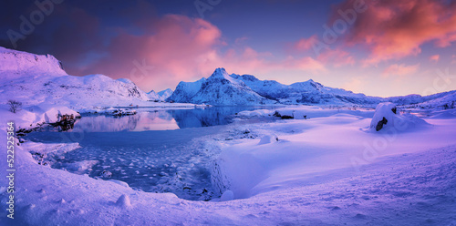 Incredible scenic evening light at sunset with blue sky and clouds in winter, northern Norway. Lofoten Islands. Fantastic Colorfull sunset over the Snowcapped Hustinden Mountains and Boosen fjord. photo