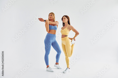 Two people is preparing for the fitness. Beautiful women in sportive clothes is indoors in the studio © standret