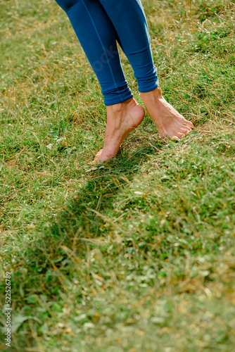 Closeup photo of female legs standing barefoot on green grass in park