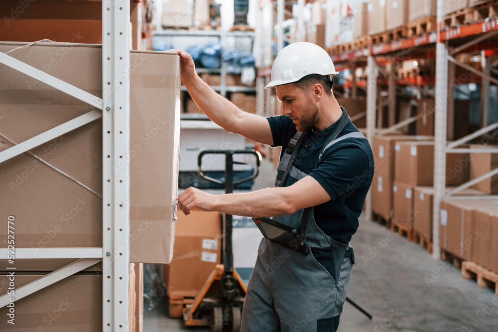 Checking the box. Employee in uniform is working in the storage at daytime Checking the box. Employee in uniform is working in the storage at daytime