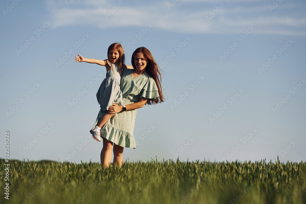 Holding girl on hands. Mother and daughter have fun outdoors on the field at summer Holding girl on hands. Mother and daughter have fun outdoors on the field at summer