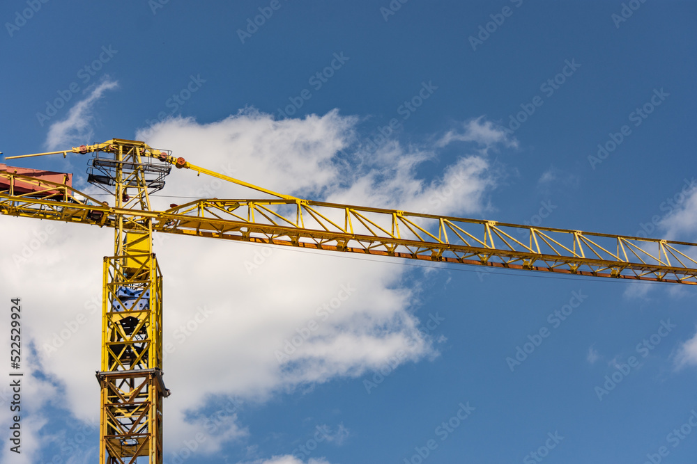 Close up to a yellow construction crane arm against a cloudy sky