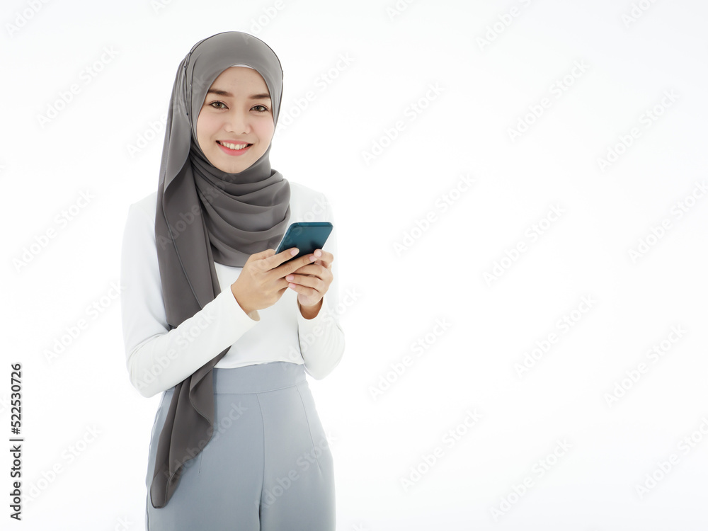 A beautiful Asian Muslim woman wearing a hijab is using a smartphone to work and communicate. Islamic woman's concept doing business and communicating A beautiful Asian Muslim woman wearing a hijab is using a smartphone to work and communicate. Islamic woman's concept doing business and communicating
