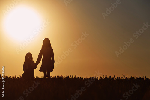 In beautiful sunlight. Majestic view. Two little girls have fun outdoors on the field at summer