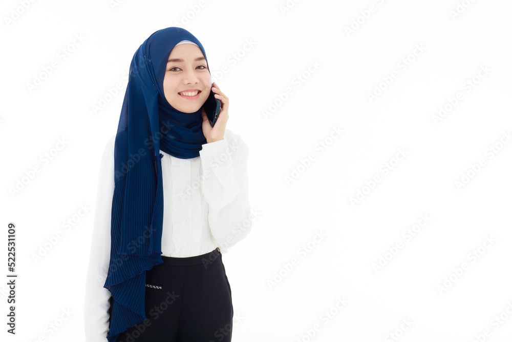 A young beautiful young Asian Muslim woman wearing headscarf is happily using her smartphone on white background. Islamic woman concept with modernity and modern communication, social relations A young beautiful young Asian Muslim woman wearing headscarf is happily using her smartphone on white background. Islamic woman concept with modernity and modern communication, social relations