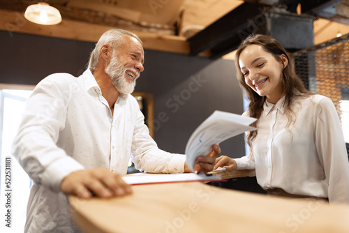 Senior man, manager making plans together with secretary, reading some documents in loft style office. Concept of business