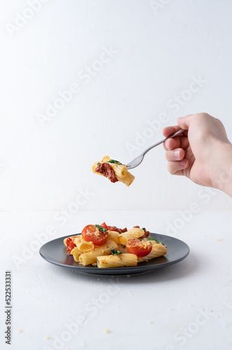 A man's hand holds a fork with pasta. Pasta on a fork. Italian dish. White background with food.