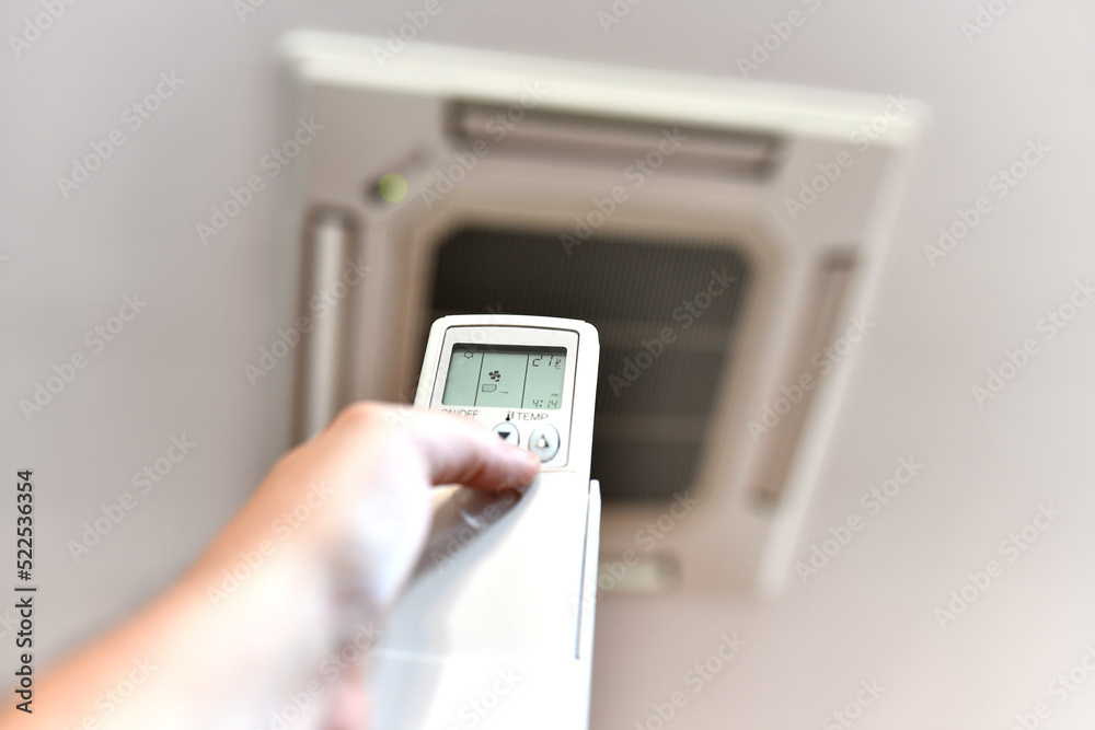 man's hand regulating the air conditioner at 27 degrees due to the energy crisis. Air conditioning or heat pump man's hand regulating the air conditioner at 27 degrees due to the energy crisis. Air conditioning or heat pump
