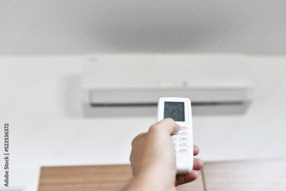man's hand regulating the air conditioner at 27 degrees due to the energy crisis. Air conditioning or heat pump man's hand regulating the air conditioner at 27 degrees due to the energy crisis. Air conditioning or heat pump