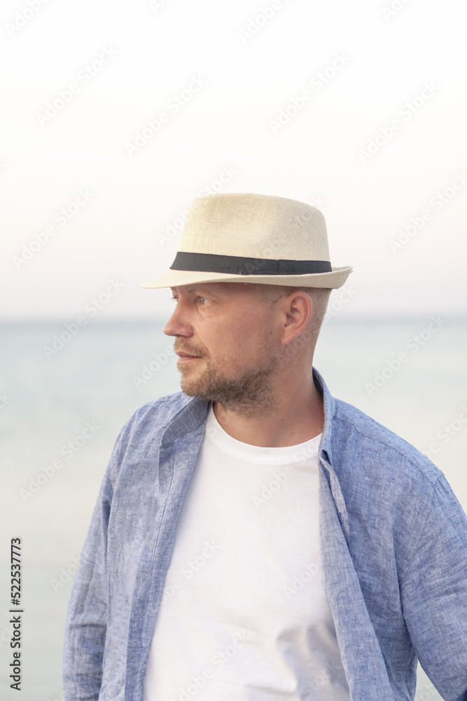 Vertical view of man in a summer hat, relaxing on vacation. Close up portrait of thinking young man. Meditation, mental health, zen concept. Summer holiday.