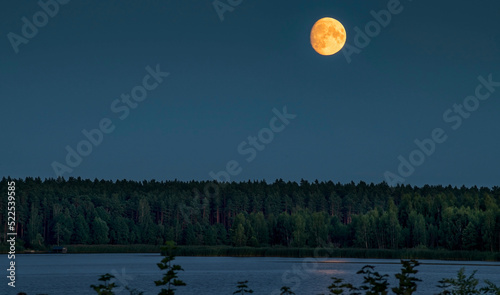 Rise of moon over lake and forest