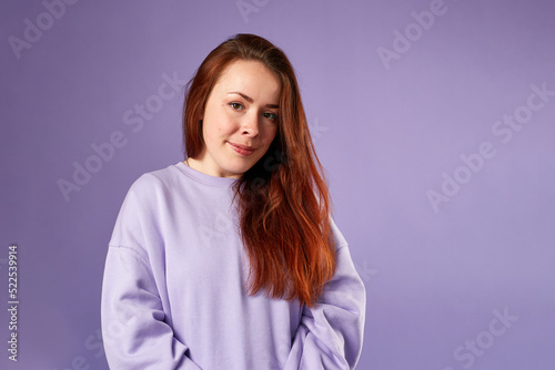 Caucasian woman in violet sweatshirt. Natural look. Smiling. long red hair. Violet background © leravalera89