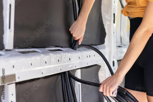 Cropped close up view of unrecognizable young woman passing through the tubes for electricity wiring in a camper van